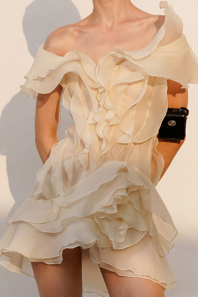 Beige ruffled dress worn by a person on a neutral background