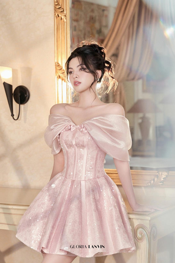 Woman in a pink off-shoulder dress standing in front of a mirror.