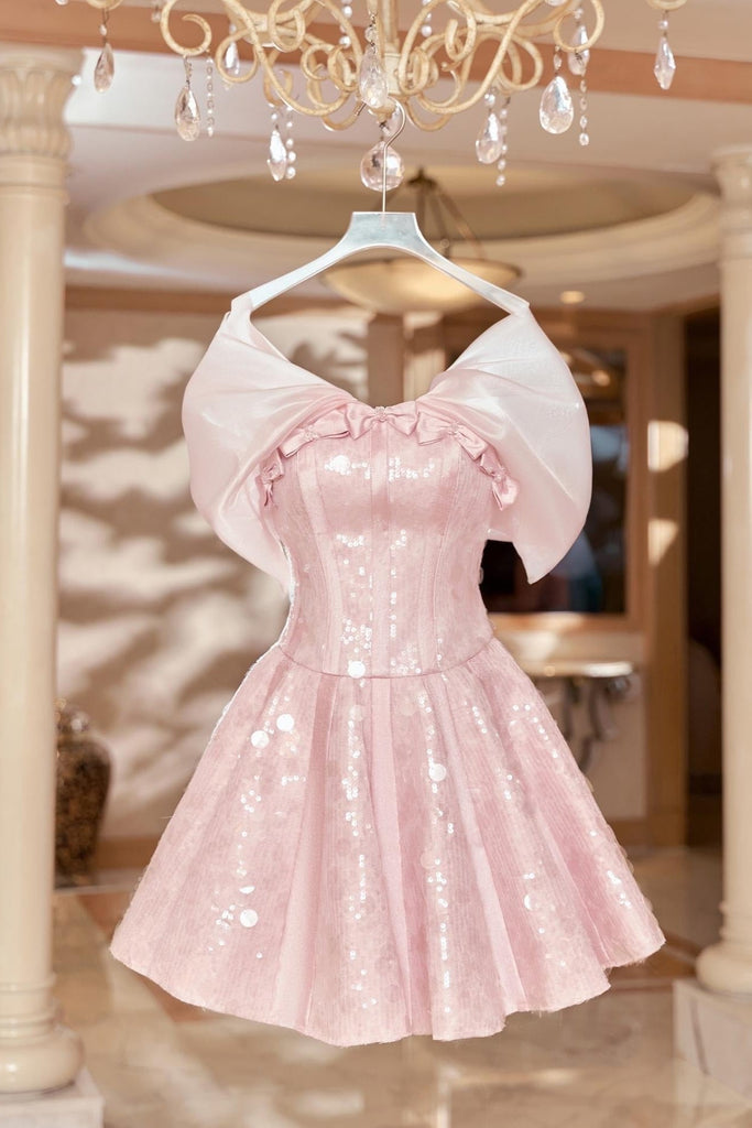 Pink sequin dress on a hanger with a chandelier in the background